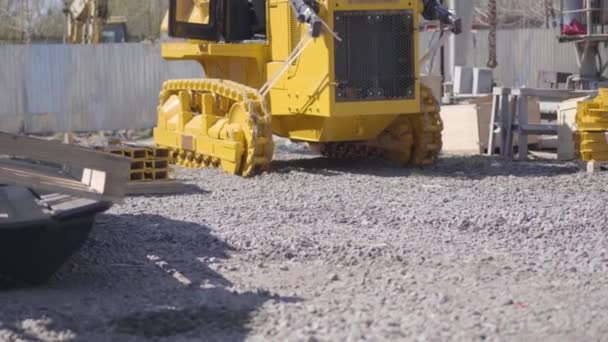 Yellow tracked tractor riding outdoors at plant. Vehicle working at factory on sunny day. Manufacture, industry, heavy equipment, business. — Stock Video
