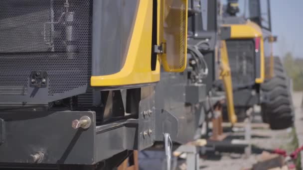 Close-up de máquinas de engenharia pesada em pé ao ar livre no dia ensolarado. Equipamento industrial amarelo na fábrica ou local de fabricação. Indústria, empresa, fabrico . — Vídeo de Stock