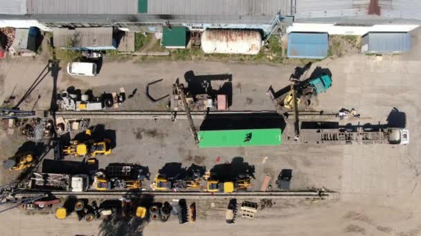 Widok z góry żurawie przemieszczające kontener na terenie przemysłowym. Widok z lotu ptaka na fabrykę w kraju trzecim. Przemysł, biznes, ładunek. — Wideo stockowe