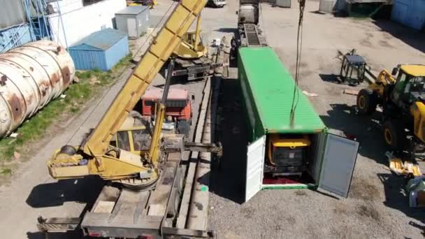 Cámara se mueve hacia arriba en la fábrica industrial en el país del tercer mundo. Contenedor de envío verde y grúas amarillas con trabajadores caminando en el sitio de construcción. Industria, negocios . — Vídeos de Stock