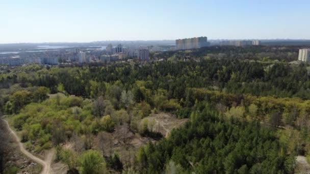 Letecký pohled na zelené předměstí s velkým městem v pozadí. Dron pohled na krásnou krajinu na slunné jaro nebo letní den. Příroda, klid. — Stock video