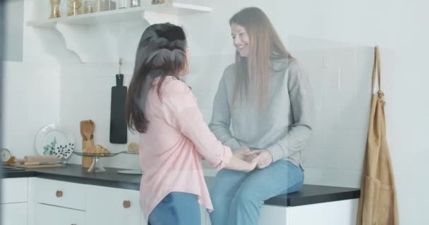 Retrato de pelirroja feliz caucásica lesbiana cogida de la mano de novia morena. Joven hermosa pareja gay femenina hablando y sonriendo en casa. Alegría, ocio, LGBT, homosexual. Sede del cine 4k ProRes . — Vídeo de stock