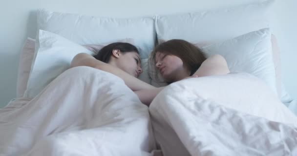 Portrait of beautiful young lesbians sleeping in bed on sunny morning. Hugging homosexual Caucasian couple resting together in bedroom. LGBT lifestyle, diversity, same sex family, Cinema 4k ProRes HQ. — Stock Video