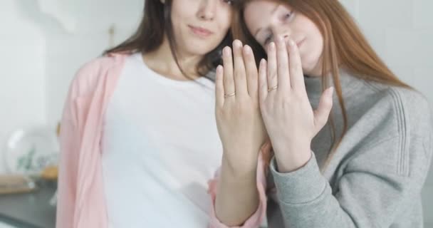 Розмита лесбійська пара показує пальці з весільними кільцями в камері і обіймами. Портрет щасливої молодої кавказької родини. ЛГБТ, гомосексуальні відносини, кохання. Фільм 4k ProRes HQ. — стокове відео
