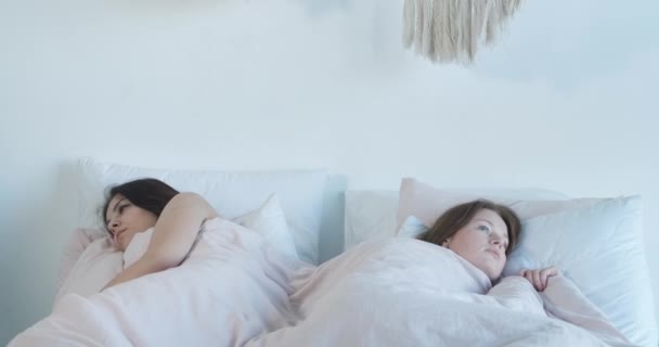 Dos mujeres hermosas sorprendidas despertando en una cama en la mañana. Retrato de lesbianas caucásicas conmocionadas cometiendo un error. Pánico, LGBT, sensualidad, relación del mismo sexo. Sede del cine 4k ProRes . — Vídeos de Stock