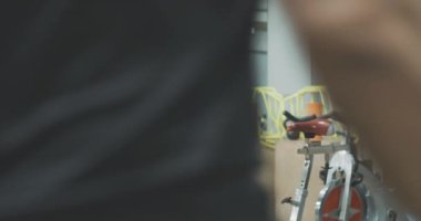 Beyaz tenli sporcuların spor salonuna girerken ve egzersiz bisikletlerinde otururken görüntüsü. Zayıf atletik erkek ve kadınlar bisiklet teçhizatı üzerine çalışmaya başlarlar. Spor, sağlık, yaşam tarzı. Sinema 4k ProRes Merkezi.