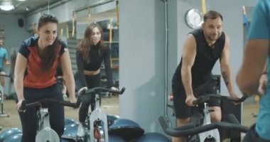 Spor salonunda bisiklet süren erkek ve kadınları destekleyen tanınmamış antrenör. Bir grup sportif atletizm sporcusu bisiklet teçhizatı eğitimi alıyor. Koçluk, spor, yaşam tarzı. Sinema 4k ProRes Merkezi.