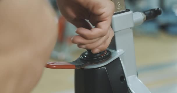 Extrême gros plan de la main blanche masculine ajustement vélo d'exercice dans la salle de gym. Jeune homme fort méconnaissable compliquant la formation sur l'équipement de cyclisme. La force, le sport. Siège social Cinema 4k ProRes . — Video