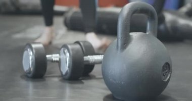 Spor salonunun arka planında bulanık, beyaz tenli sporcunun el ağırlığını alıp ayrıldığı yakın çekim. Tanınmayan adam kaslarını çalıştırıyor. Sağlıklı yaşam tarzı kavramı. Sinema 4k ProRes Merkezi.