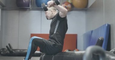Spor salonunda el ağırlığını kaldıran kendine güvenen bir adamın yan görünüşü. Spor kulübünde spor yapan yakışıklı, beyaz tenli bir sporcu. Güç, dayanıklılık, yaşam tarzı, spor. Sinema 4k ProRes Merkezi.