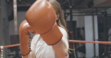 Güzel kadın boksör boks kamerasının portresi. Spor salonunda boks ringinde havayı yumruklayan hoş, zayıf, beyaz bir kadının yakın çekimi. Cinsiyet eşitliği kavramı. Sinema 4k ProRes Merkezi.