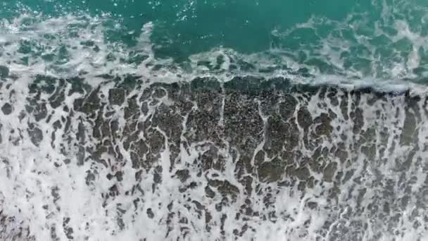 Ondas claras espumosas rolando em seixos. Vista superior da água do mar Mediterrâneo na praia de seixos. Sea shore no dia ensolarado em Chipre resort turístico. Close-up. paisagem marinha, litoral, beleza na natureza . — Vídeo de Stock