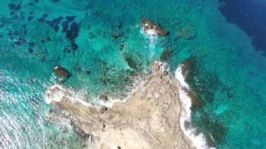 Terkedilmiş kayalık sahilde kristal berrak su manzarası. Kıbrıs Rum Kesimi Akdeniz kıyısının şeffaf dalgalarının hava manzarası. Çevre, turizm, güzellik, doğa, deniz manzarası.