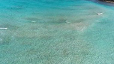 Üzerinde Akdeniz 'in turkuaz dalgaları olan kumlu deniz diplerinin son derece geniş bir görüntüsü. Köpüklü şeffaf suyla muhteşem Kıbrıs tatil beldesinin hava manzarası. Turizm, tatiller, doğa.
