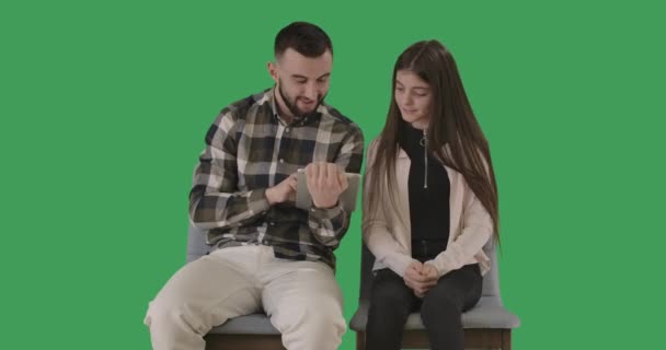 面白い十代の女の子は彼女のタブレット画面と話を示す男として交差する手をジェスチャーしません。父と娘は、インターネットサーフィンやソーシャルメディアを使用しています。クロマキー、緑の画面。シネマ4k｜ProRes HQ. — ストック動画
