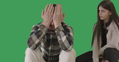 Şaşırmış genç bir kız gözlerini ovuşturan, ağlayan ve şakakta parmak büken bir adama bakıyor. Esmer, beyaz bir kız, üzgün bir babaya delice davranışlar sergiliyor. Kromakey. Sinema 4k ProRes Merkezi.