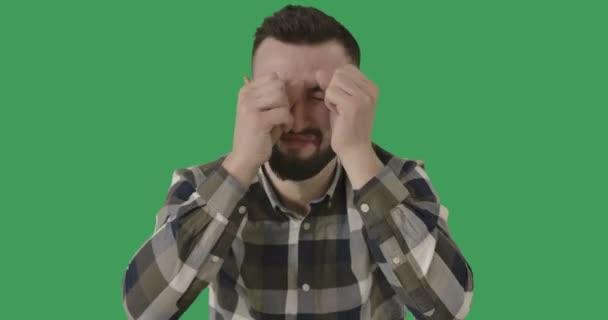 Portrait of crying Caucasian handsome man at green screen background. Brunette depressed guy rubbing eyes. Sadness, depression, loneliness. Chromakey. Cinema 4k ProRes HQ. — Stock Video