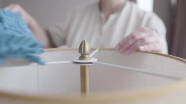 Tanınmayan otel hizmetçisi lamba temizliği için toz fırçası kullanıyor. Profesyonel Kafkas üniformalı kadın otel odasını temizliyor. Hizmet, turizm, yaşam tarzı, meslek.