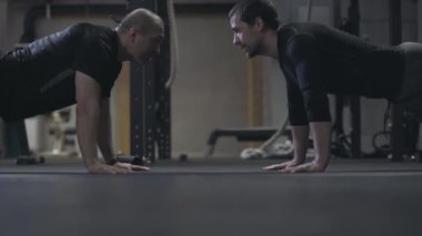 Spor salonunda itişen yetişkin erkeklerin yan görüntüsü. Genç, sağlıklı, beyaz sporcular spor salonunda spor yapıyor. Erkeklik kavramı, spor, kas yapısı, yaşam tarzı..