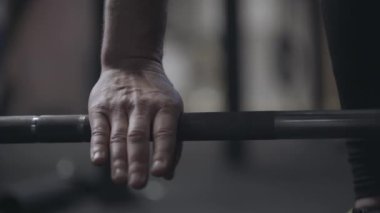 Beyaz erkek el kaldırıyor ve halteri indiriyor. Tanınmayacak kadar güçlü bir sporcu spor salonunda ağırlık kaldırıyor. Spor, halter, ağırlık kaldırma, vücut geliştirme, sağlıklı yaşam tarzı..