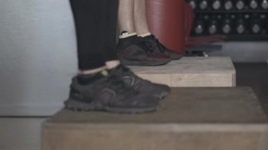 Beyazlar spor salonunda kutuların üzerine atlıyorlar. Spor salonundaki atletik erkek ve kadının çapraz formda çalışması. Sağlık, yaşam tarzı, spor.
