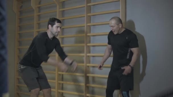 Muž trenér podporující mladé brunetky muž cvičení s crossfit lana. Zdravý pohledný běloch cvičí v tělocvičně. Sport, životní styl, mužnost, podpora, koučování. — Stock video