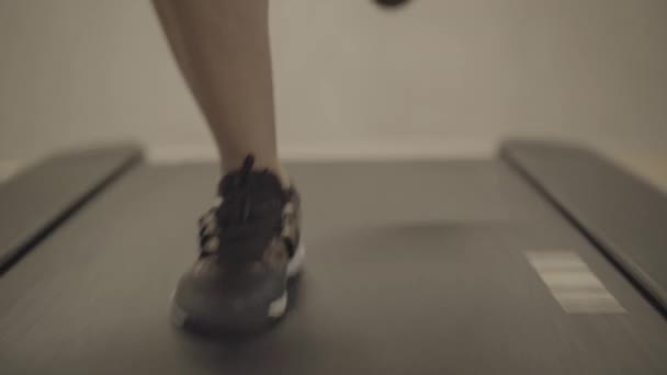 Vooraanzicht close-up van mannelijke benen joggen op loopband in fitnessclub. Onherkenbare jonge atletische sportieve blanke man draait op apparatuur in de sportschool. Oefening, training, sport, levensstijl. — Stockvideo