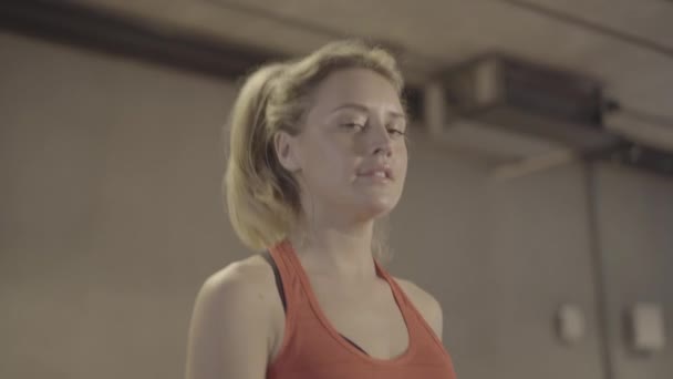 Blond brown-eyed Caucasian woman walking on treadmill and looking at camera. Close-up portrait of confident young sportswoman exercising in gym. Fitness, lifestyle, sport, beauty. — Stock Video