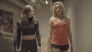 Spor salonunda gezinen ve konuşan ciddi atletik kadınlar. Kendine güvenen güzel sporcu kadınların sohbet edişinin portresi spor ekipmanları boyunca yürüyormuş gibi. Spor, spor, yaşam tarzı, güzellik, kilo kaybı.