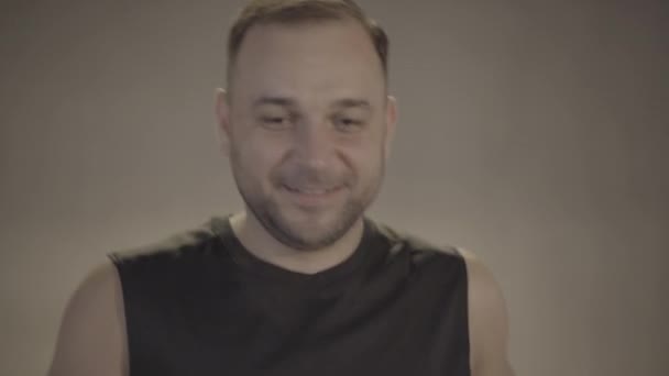 Gros plan d'un homme brune souriant faisant du jogging dans une salle de gym. Portrait d'un beau jeune sportif confiant faisant de l'exercice sur tapis roulant. Bien-être, sport, mode de vie sain, confiance . — Video