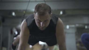 TRX kayışlarıyla kendine güvenen ciddi sporcunun portresi. Spor salonunda antrenman yapan genç, konsantre beyaz bir adam. Egzersiz, sağlık, spor, yaşam tarzı..