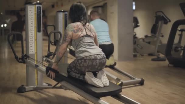Vue arrière de la femme et de l'homme caucasiens faisant de l'exercice de gravité. Sportive brune tatouée et jeune sportif entraînant les muscles dans la salle de gym. Bien-être, mode de vie sain, sport, fitness . — Video