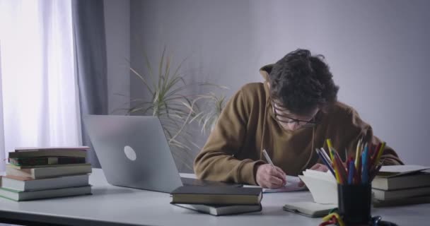 Emocionado chico nerd caucásico escribiendo rápido en el teclado portátil. Estudiante universitario absorbido buscando información para el proyecto en Internet. Educación, diligencia, estudio. Sede del cine 4k ProRes . — Vídeo de stock