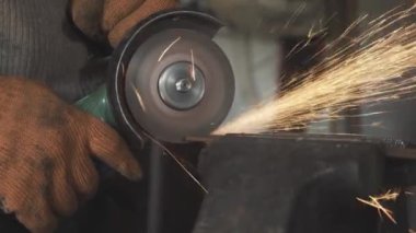 Erkek ellerinin metali öğütme makinesiyle kestiği yakın plan görüntüler. Çalışan eldiven giymiş tanınmayan bir adam. Parlatıcı aletle bir şeyler üretiyor. Esnaflar, hobi, meslek, yaşam tarzı.