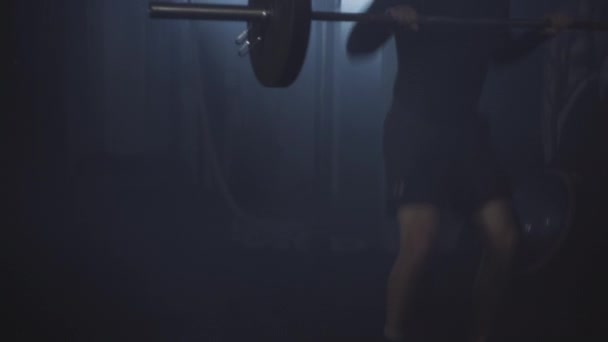 Amplio tiro de atlético guapo morena deportista levantando pesas en la luz de fondo brumosa. Retrato de hombres caucásicos fuertes y confiados entrenando los músculos en el gimnasio brumoso. Culturismo, deporte, estilo de vida . — Vídeos de Stock