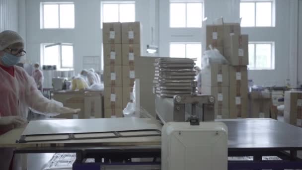 Femme caucasienne mettant feuille de papier dans la machine de découpe et la collecte des couvertures coupées pour les récipients de plat de nourriture. Vue d'ensemble de l'emballage de fabrication en usine. Convoyeur, entreprise, industrie de production. — Video