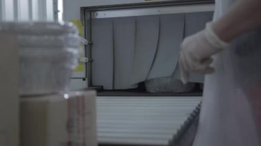 Beyaz kadın eller elektrikli süpürge makinesinden paketlenmiş bulaşık kaplarını alıyor. Üretim hattında ekipmanla çalışan tanınmayan bir kadın. İş, taşıyıcı, endüstri, üretim.