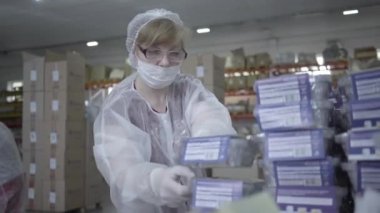 Fabrikada çalışan yüz maskeli ciddi bir kadının portresi. Yiyecek kapları üretim alanında çalışan yetişkin beyaz kadın çalışanlar. İstihdam, imalat, Covid-19 salgın işi.