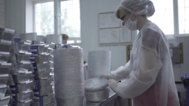 Профессиональная женщина в маске для лица хранит готовую продукцию на заводе. Портрет белой женщины, работающей на заводе по производству пищевой упаковки. Карантин, производство, бизнес . — стоковое видео