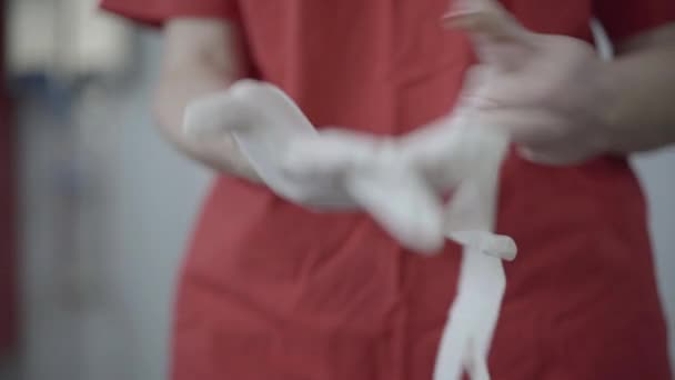 Detailní záběr ženských bělošských rukou, jak si nasazují ochranné rukavice. Neznámá žena v červených šatech se připravuje na práci na pandemickém uzamčení Covid-19. Obchod s karanténou koronaviru. — Stock video