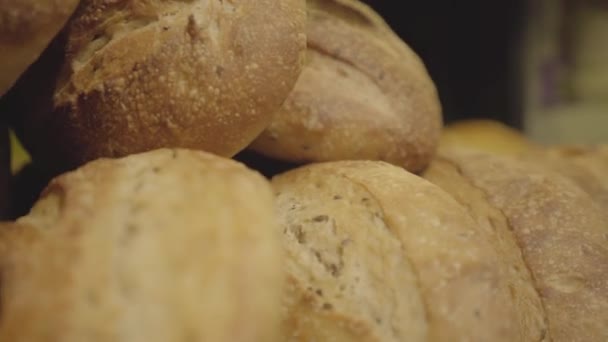 Eine Reihe frisch gebackener Brotlaibe liegt im Regal eines Lebensmittelgeschäfts. Kamera bewegt sich von rechts nach links entlang der würzigen Bäckerei im Supermarkt. Einzelhandel, Lebensmittel. S-Log 2. — Stockvideo