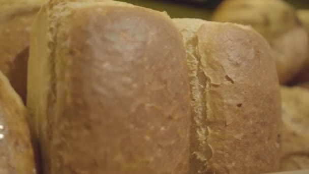 Câmera se movendo ao longo da prateleira com pão fresco assado. Close-up de deliciosa padaria deitada em supermercado para venda. Comida, compras, conceito de alimentação saudável. S-log 2 . — Vídeo de Stock