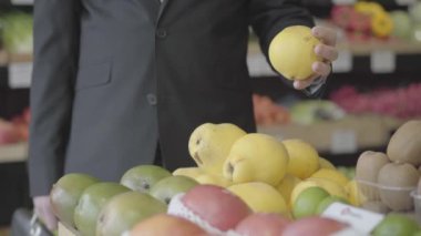 Marketten sarı armut seçen tanınmamış beyaz bir adam. Erkek vejetaryen perakende dükkanından meyve seçiyor. Yaşam tarzı, sağlıklı beslenme, vitamin yiyeceği. S-log 2.