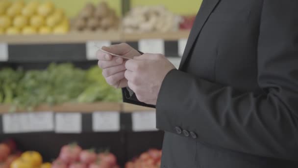Kaukázusi férfi kézen fogva tartja Bill-t a boltban. Felismerhetetlen elegáns öltönyös férfi, aki átnézi a szupermarketes vásárlások árát. Pénzügyek, életmód, élelmiszerköltségek. S-log 2. — Stock videók