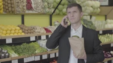 Genç, ciddi, beyaz bir adam markette telefonu kapatıp iç çekiyor. Kendine güvenen iş adamı süpermarketten alışveriş yapıyor. Yaşam tarzı, zenginlik, iş, tüketim. S-log 2.