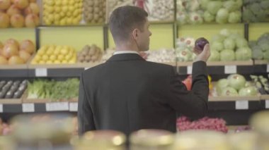 Bakkalda kırmızı soğan kokusu alan esmer, genç, beyaz bir adam. Süpermarkette sebze seçen takım elbiseli yetişkin bir adam. Vejetaryenlik, aşçılık, yaşam tarzı. S-log 2.