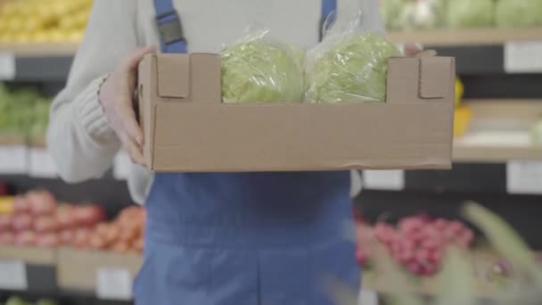 Hombre caucásico manos caja de estiramiento con coles frescas a la cámara. Empleado masculino irreconocible mostrando comida vegetariana saludable en el supermercado. Comercio, retail, negocios, vegetarianismo. S-log 2 . — Vídeos de Stock