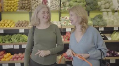 Markette konuşan ve gülen Kafkasyalı kadınlar. Sarışın ev kadınları perakende dükkanında alışveriş yaparken sohbet ediyorlar. Yaşam tarzı, neşe, tüketim, sağlıklı beslenme. S-log 2.