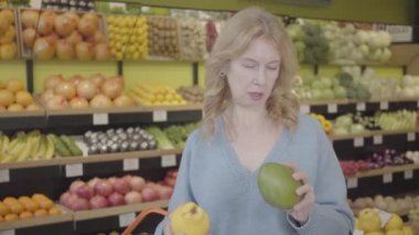 Mandalina ve armutla gelen kız arkadaşı olarak markette meyve seçen ciddi bir beyaz kadının portresi. Ev hanımları süpermarketten organik gıda alıyor. S-log 2.
