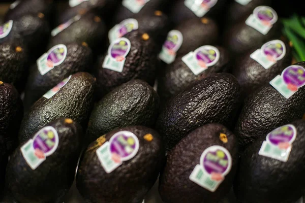 Авокадо з розмитими етикетками, що лежать в супермаркеті. Група свіжих органічних харчових фруктів у роздрібній торгівлі. Вітаміни, здорове харчування, дієта . — стокове фото